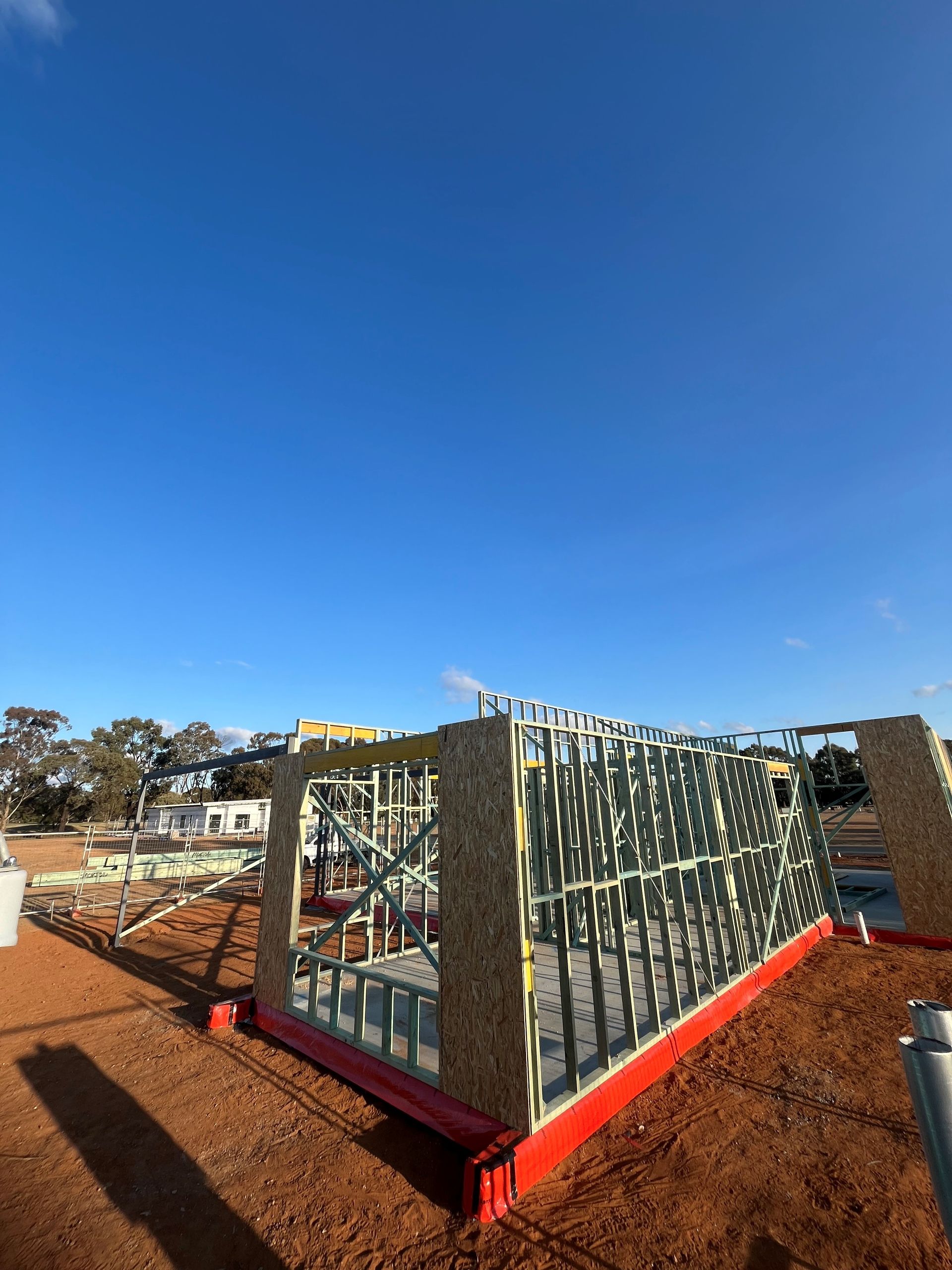 Construction site with partially framed building against a clear blue sky. 