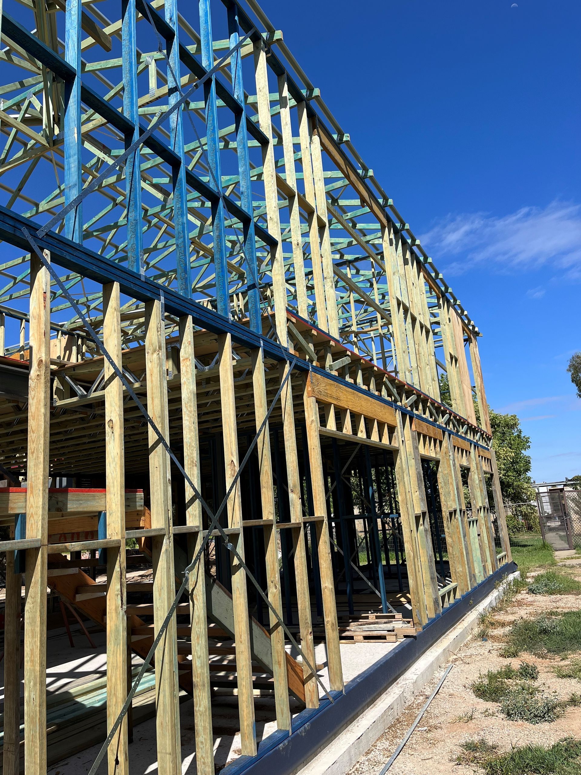 Wooden framework of a building under construction against a blue sky. 