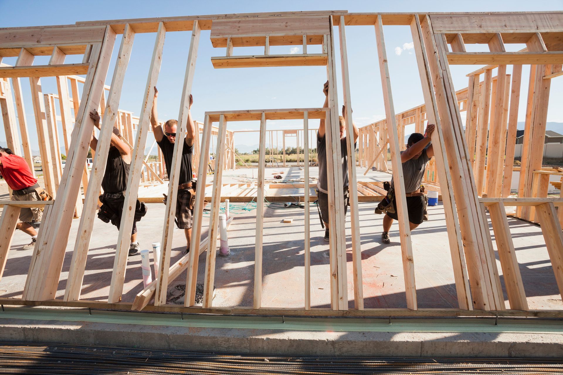 Image of workers lifting a frame on a construction site.
