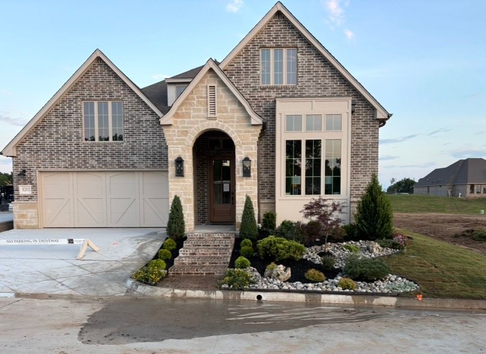 Brick suburban house with arched entry, large windows, and landscaped front yard