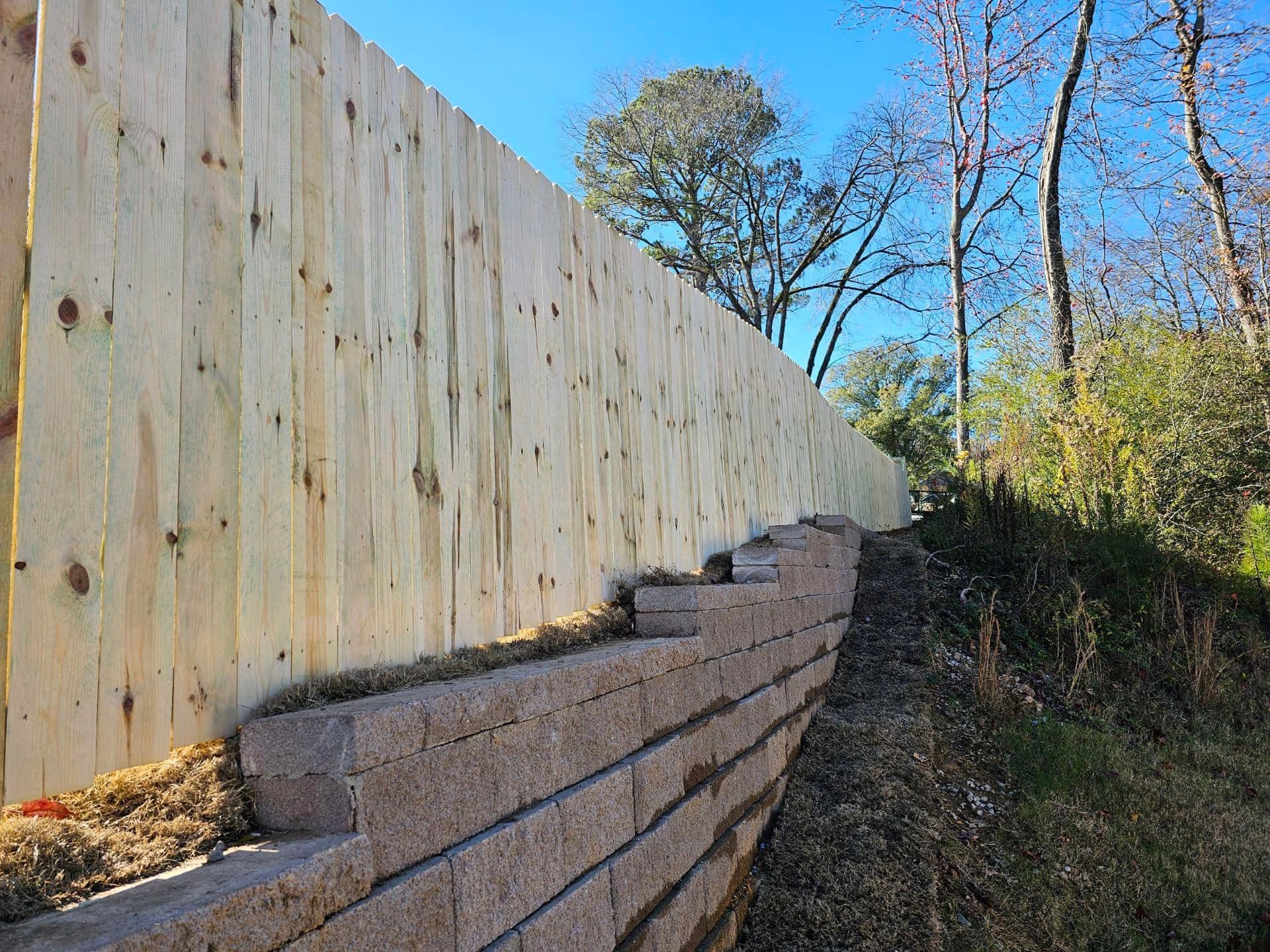 A wooden fence is being built next to a stone wall.