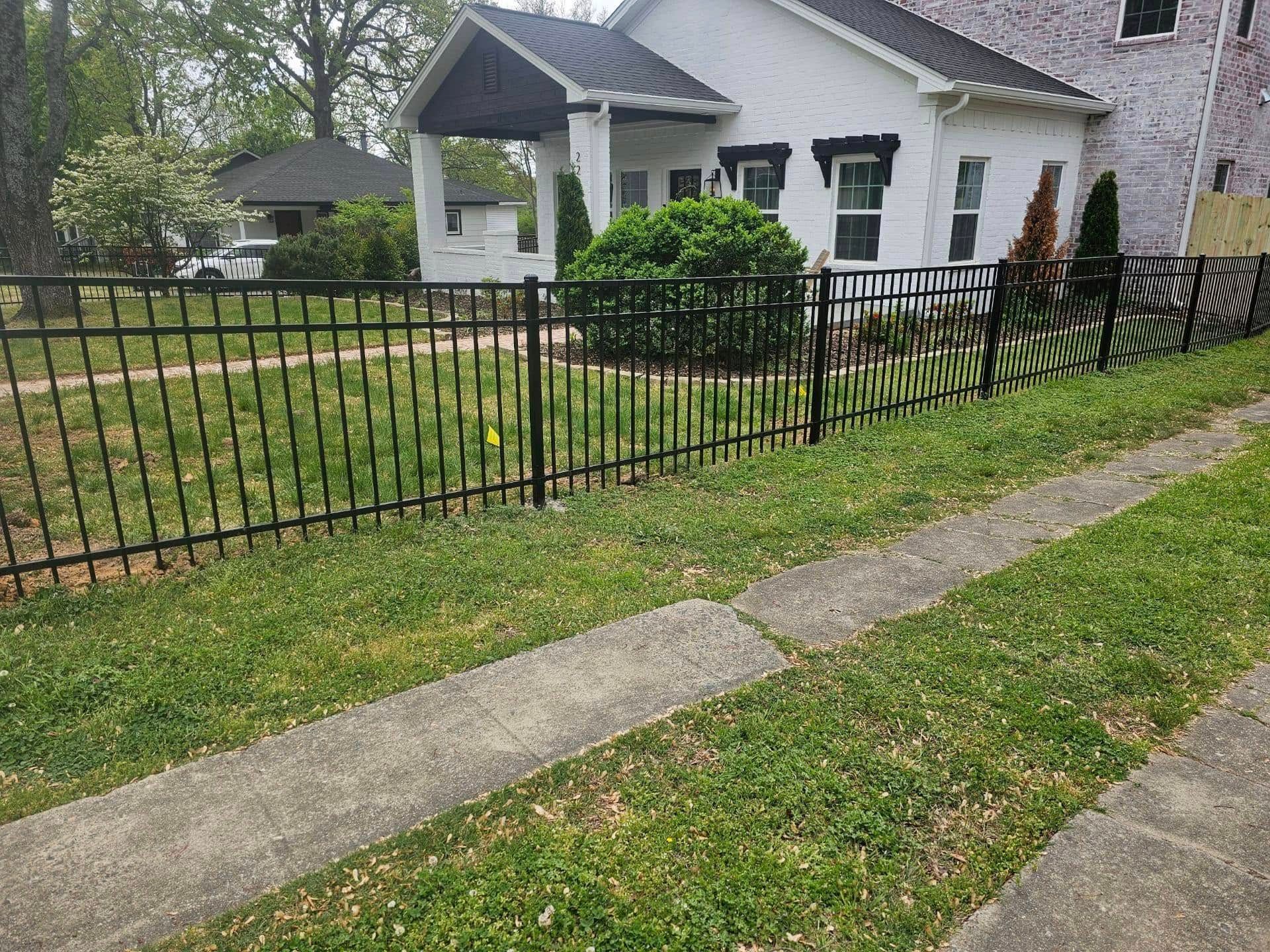 There is a black fence in front of a white house.