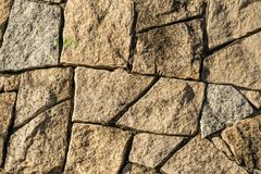 Close-up of tan stone wall with irregular textured blocks and dark mortar lines