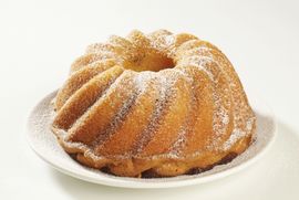 Ciambella spolverata di zucchero a velo su un piatto bianco