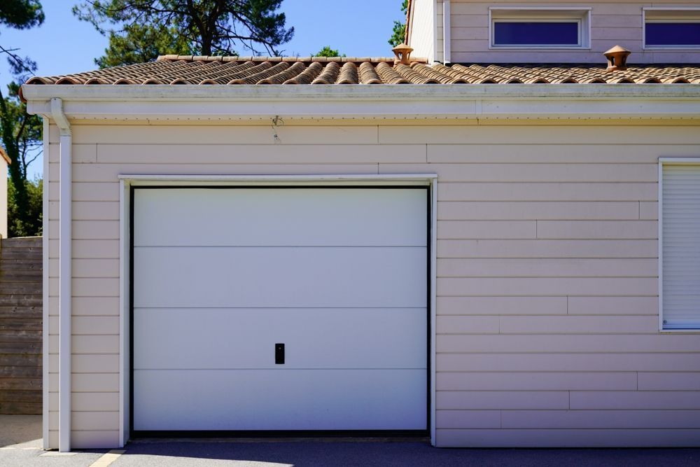 White Garage Door on a Light Pink Building — Duncan's Doors In Warwick, QLD