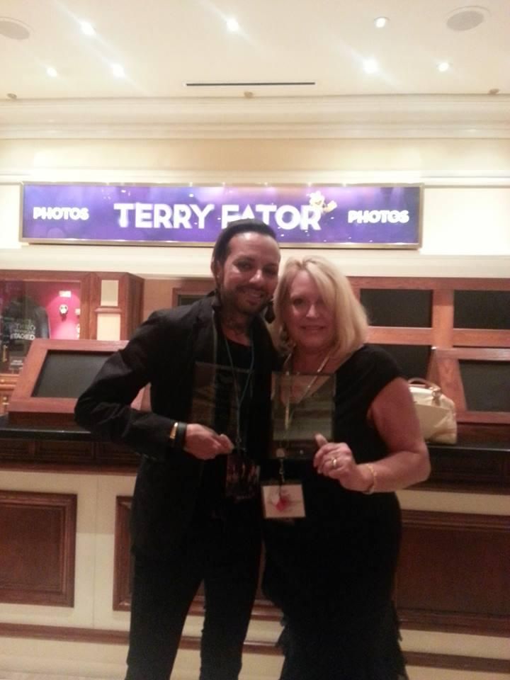 Two people posing together in front of a Terry Fator photo booth sign