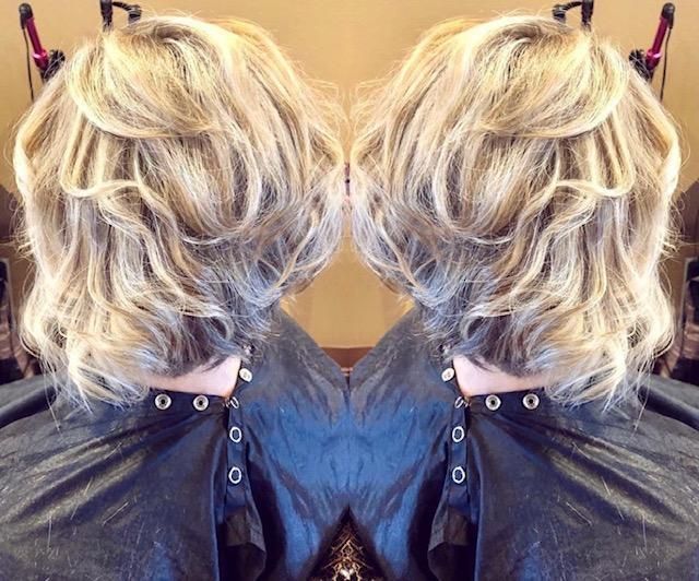 Mirror view of short blonde wavy hair styled up, shown from the back