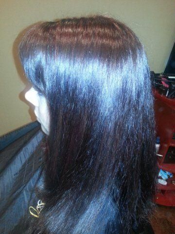 Side view of a person with long, straight dark brown hair with a blue sheen indoors