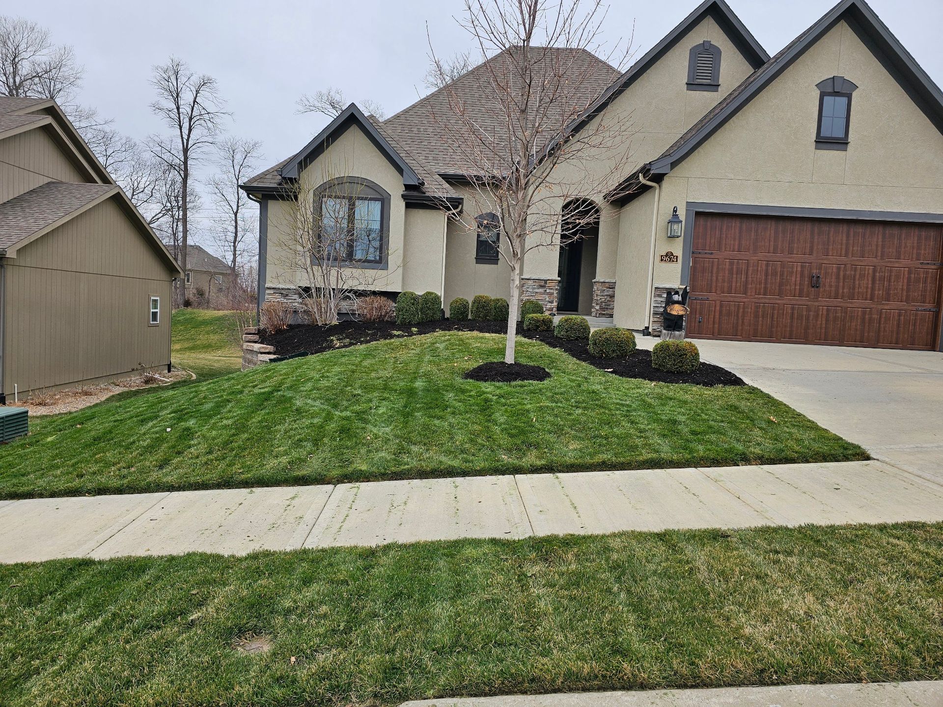 Green lawn bordered by rock edging and newly planted shrubs