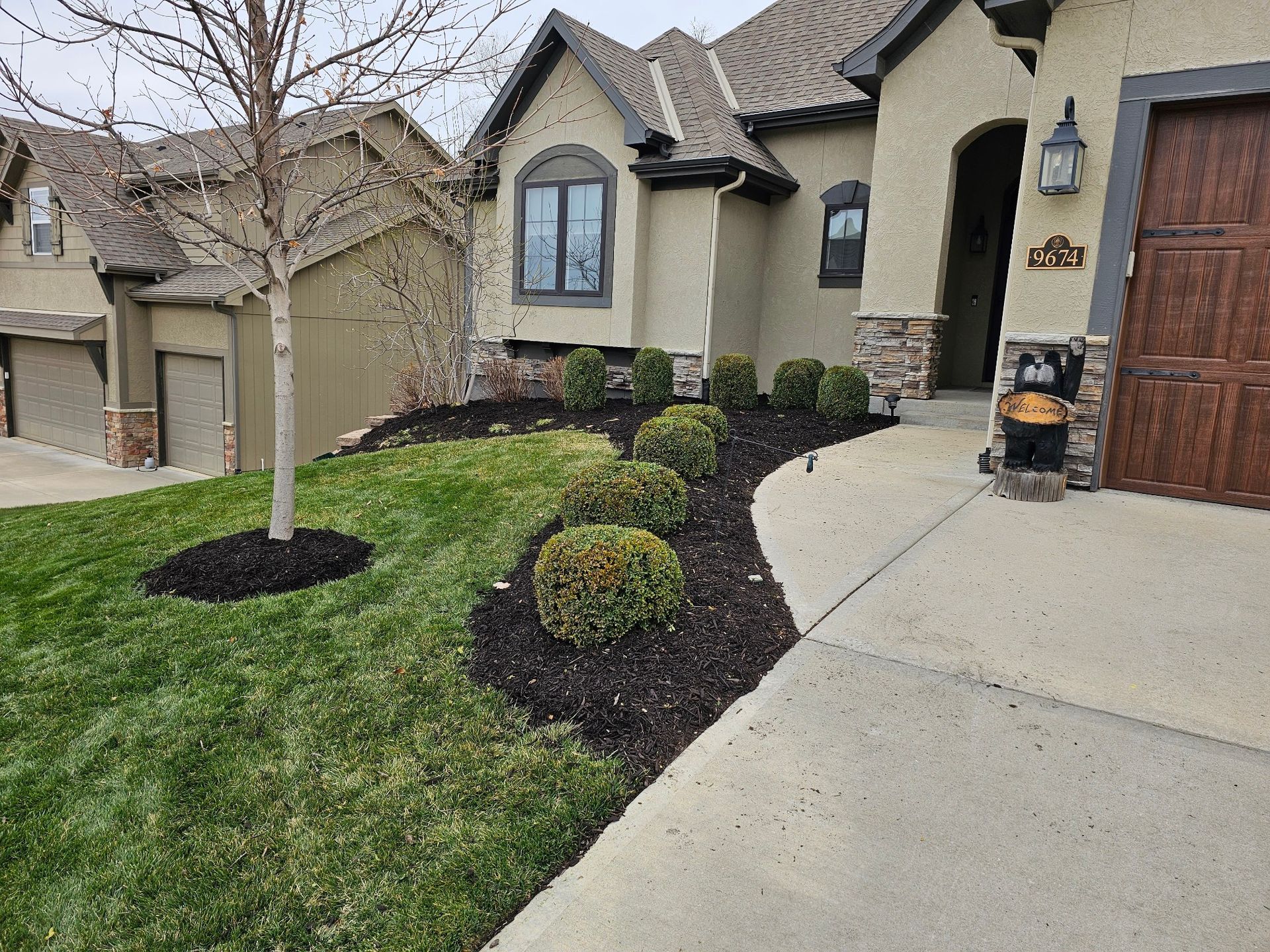 Landscaped front yard featuring mulch beds, decorative stones, and vibrant grass