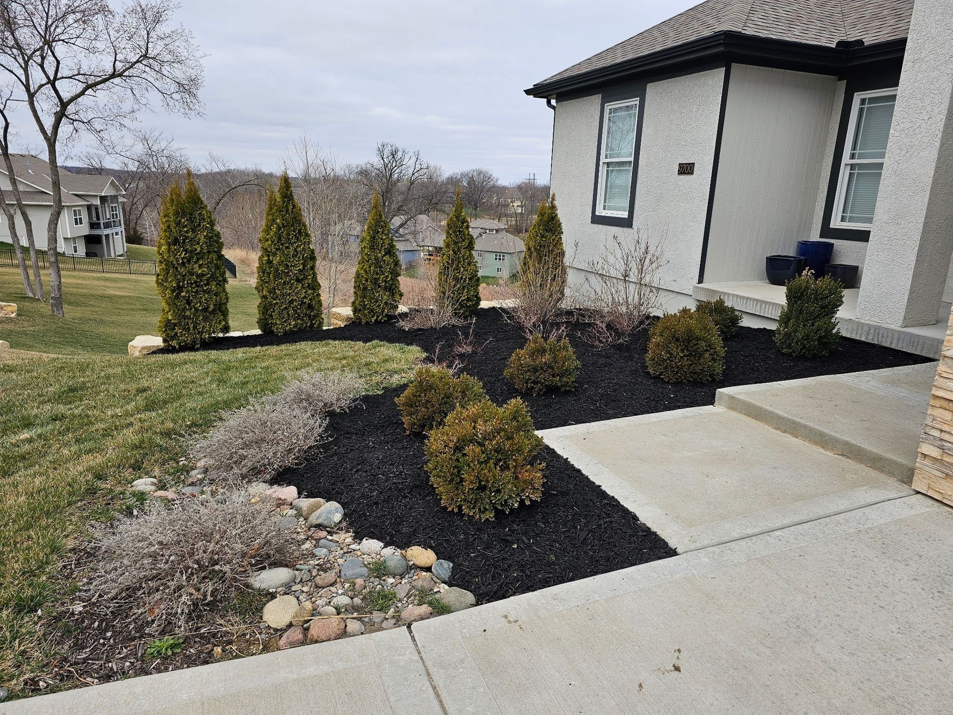 Landscaping crew enhancing a front yard with fresh mulch and stone borders