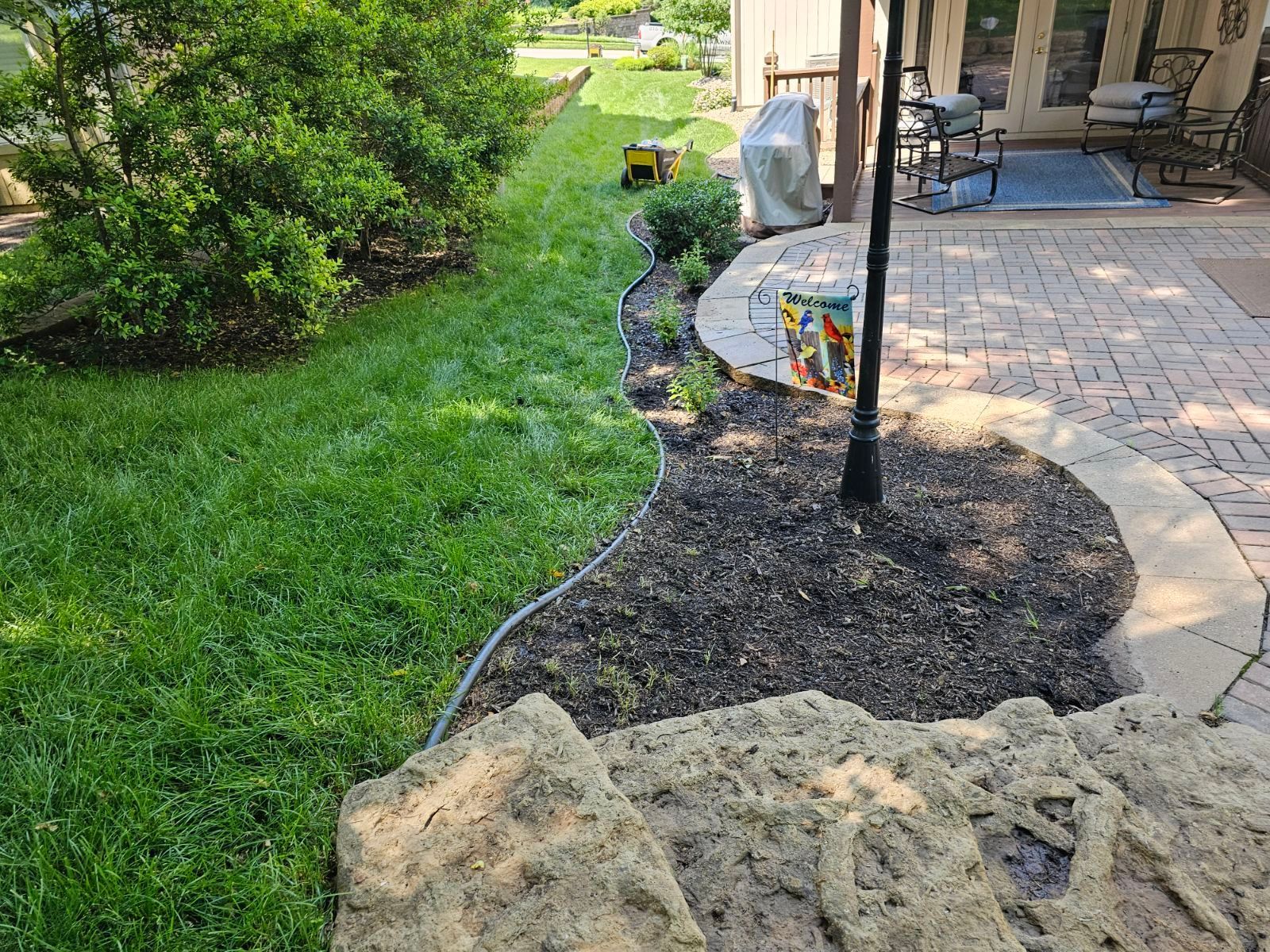 Home exterior with revitalized landscaping, rock beds, and lush green grass