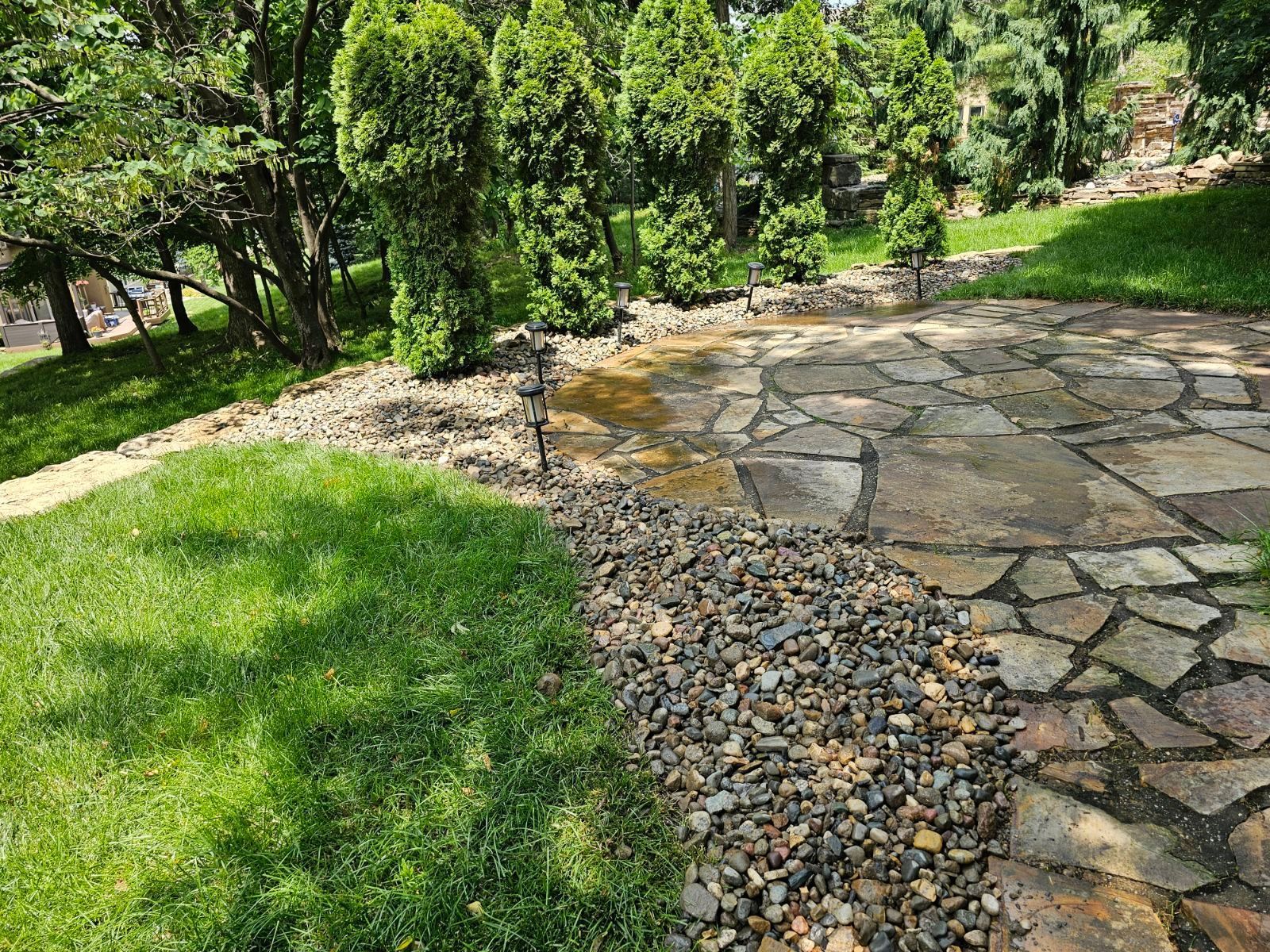 Landscape team installing decorative stones along a freshly mowed lawn