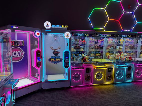 Colorful arcade game booths with neon lights and hexagonal wall lights in a dark room