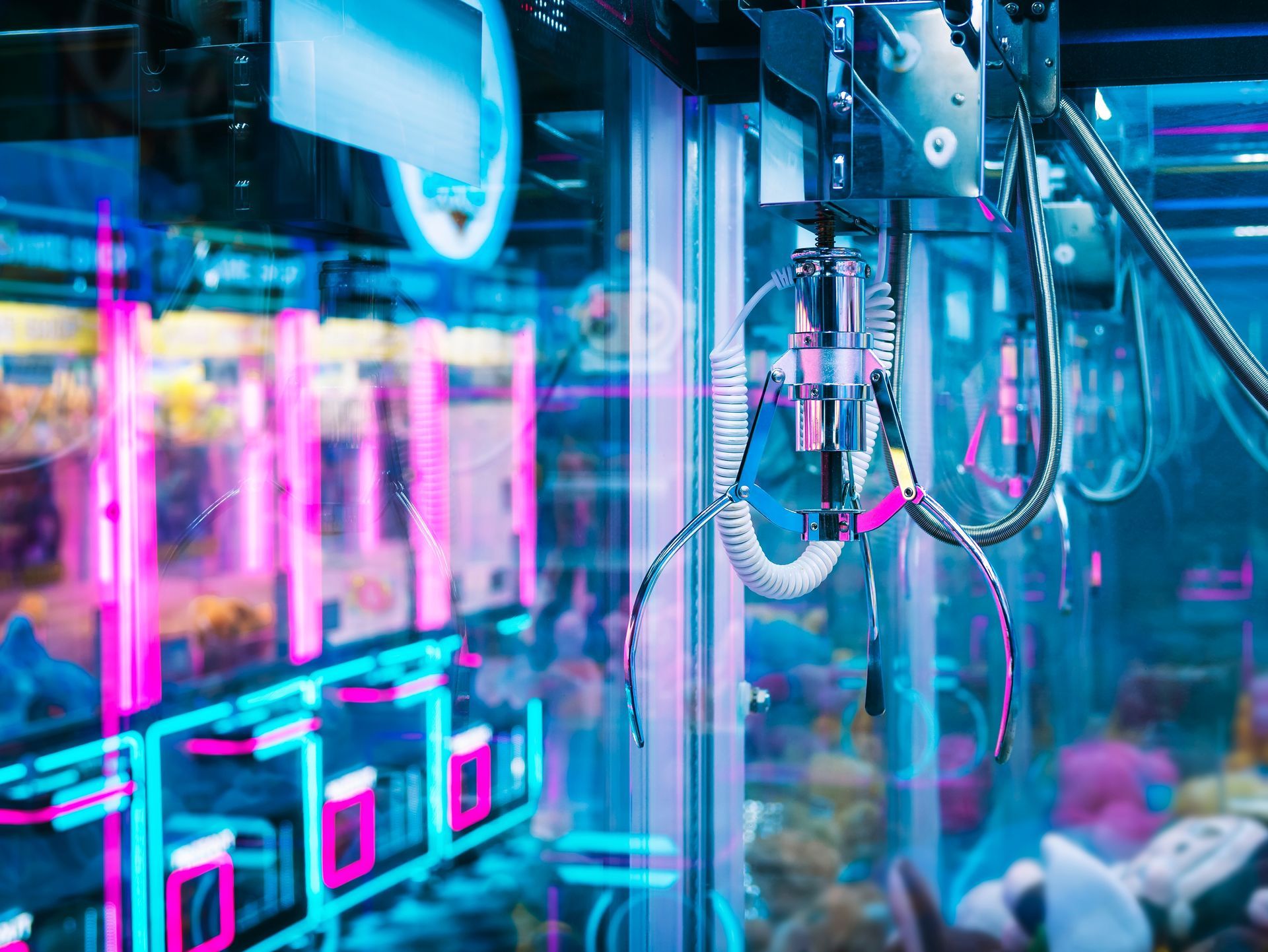 Robotic arms inside a glass industrial machine lit with blue and pink neon lights