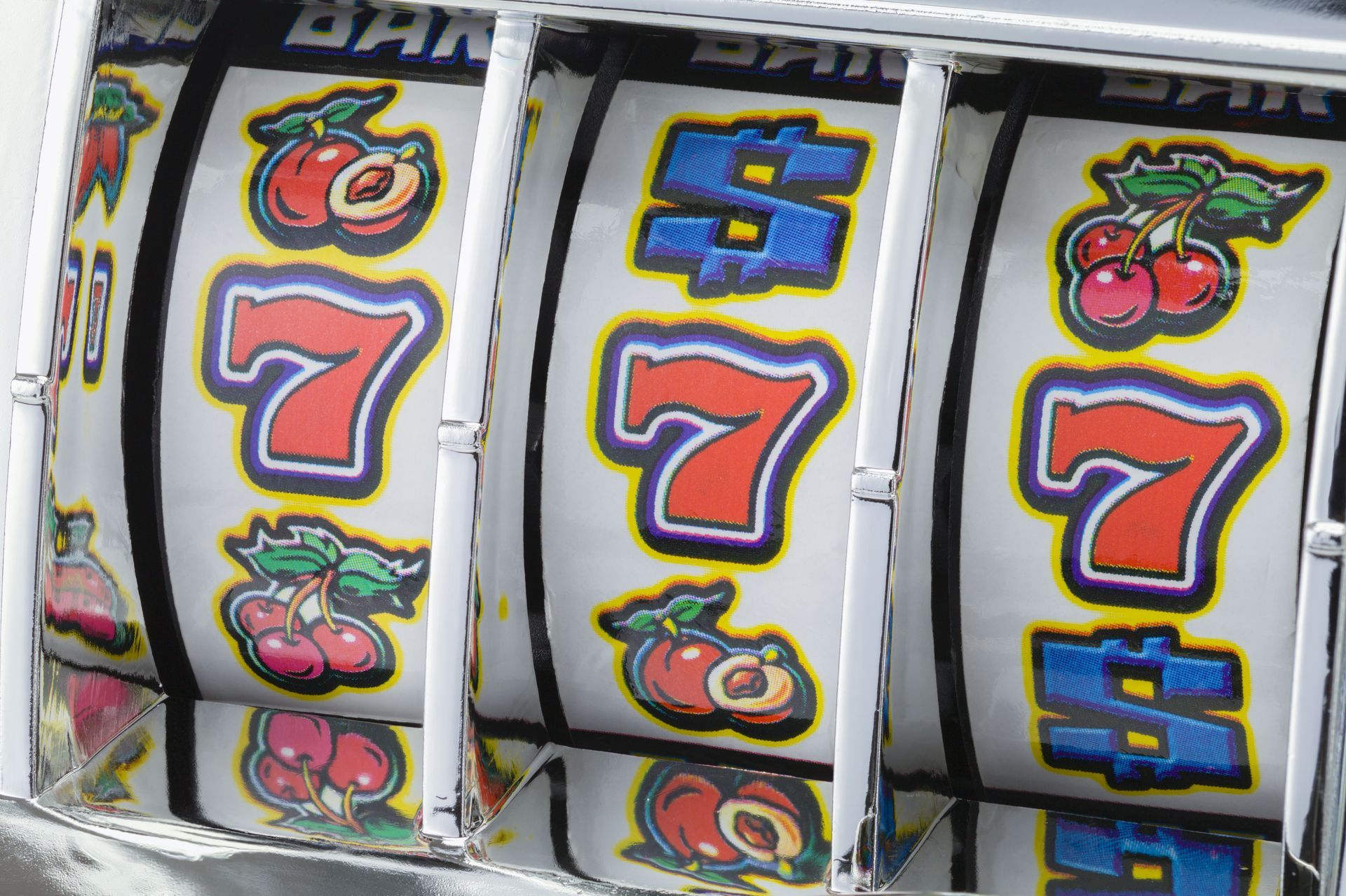 Close-up of slot machine reels showing red 7s and fruit symbols