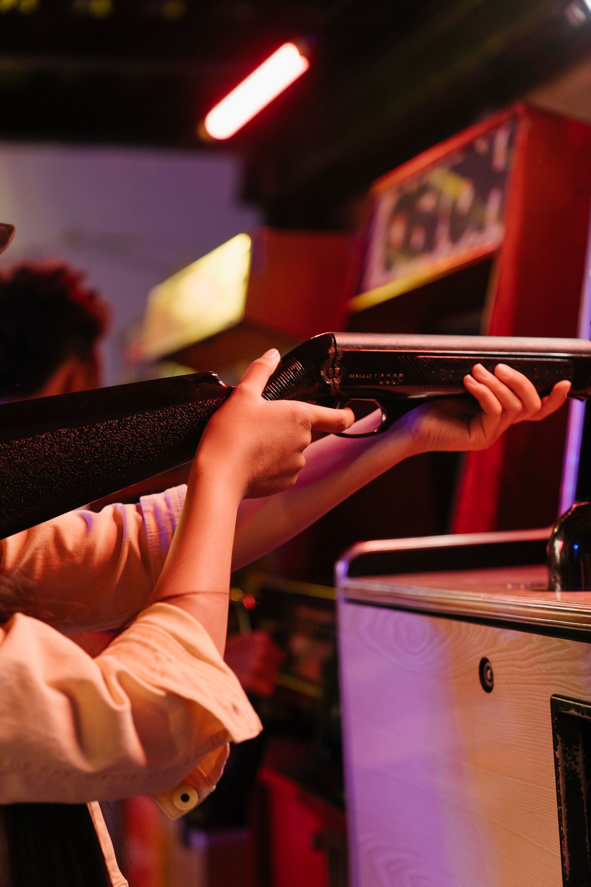 Hands gripping a black amusement ride safety bar under colorful lights