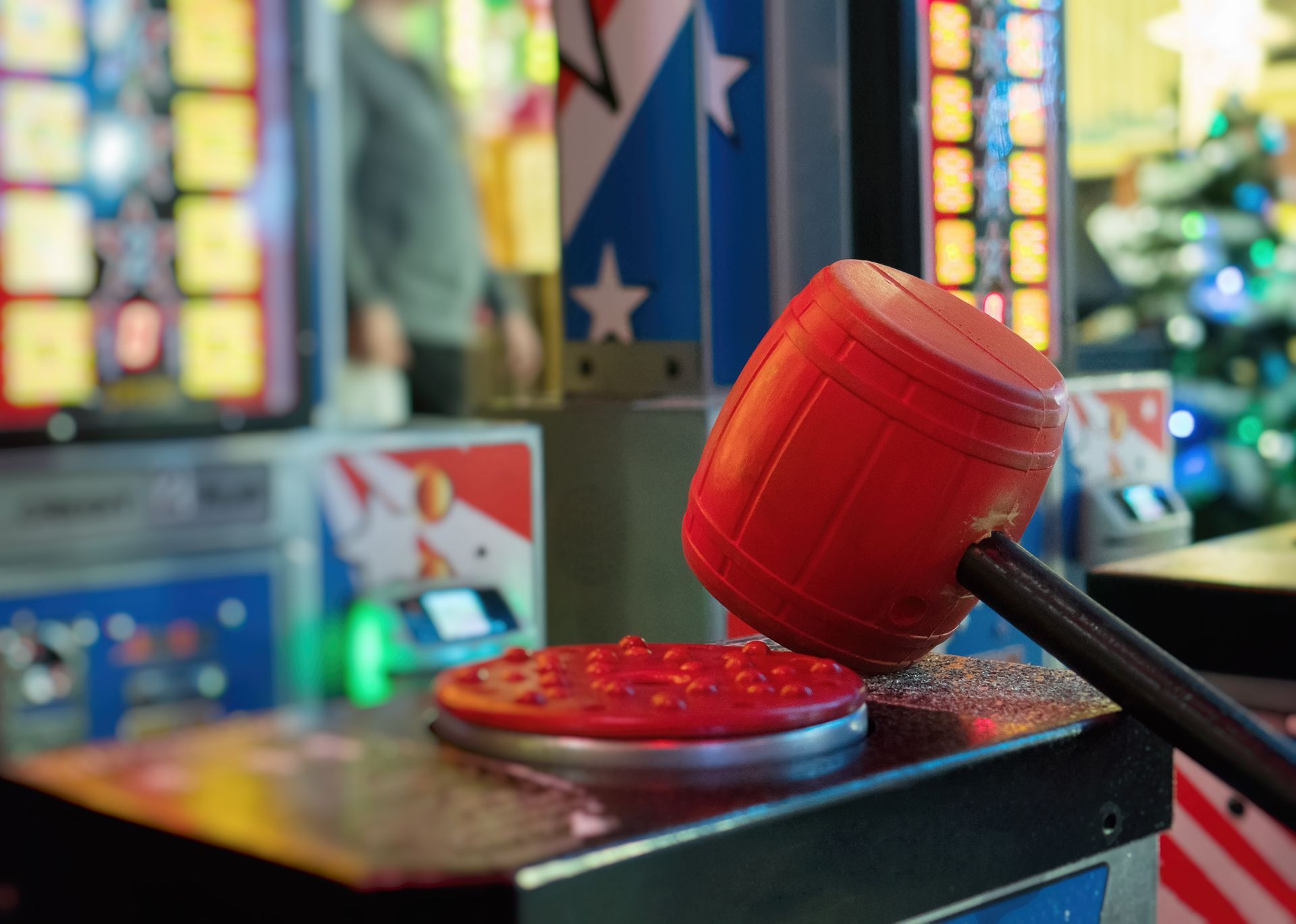 Red toy gavel striking a red button in an arcade-like setting