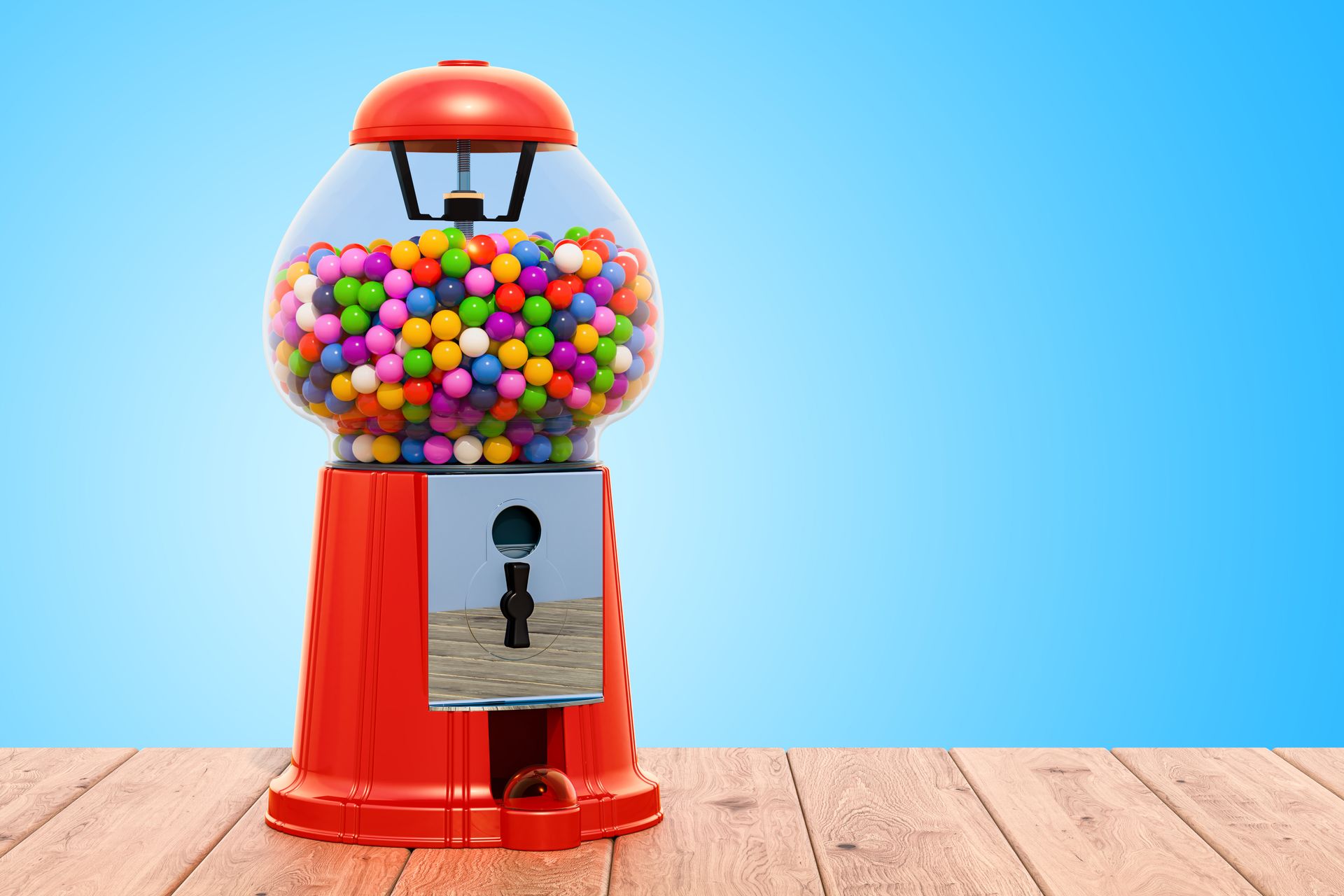 Red gumball machine filled with colorful candies on a wooden surface against a blue background