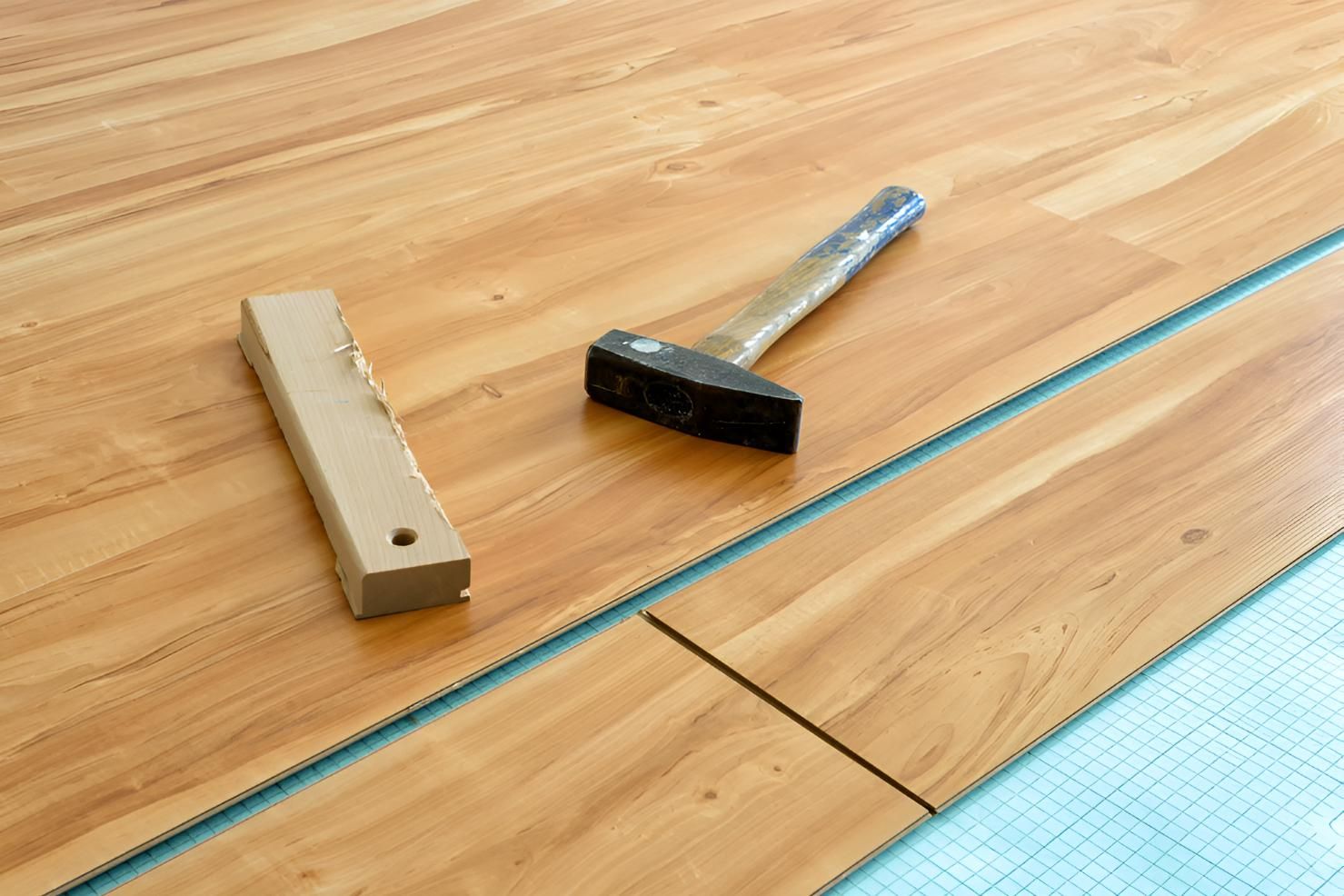 Hammer and a Piece of Wood Are on a Vinyl Planks — Affordable Carpets & Mats in Elimbah, QLD