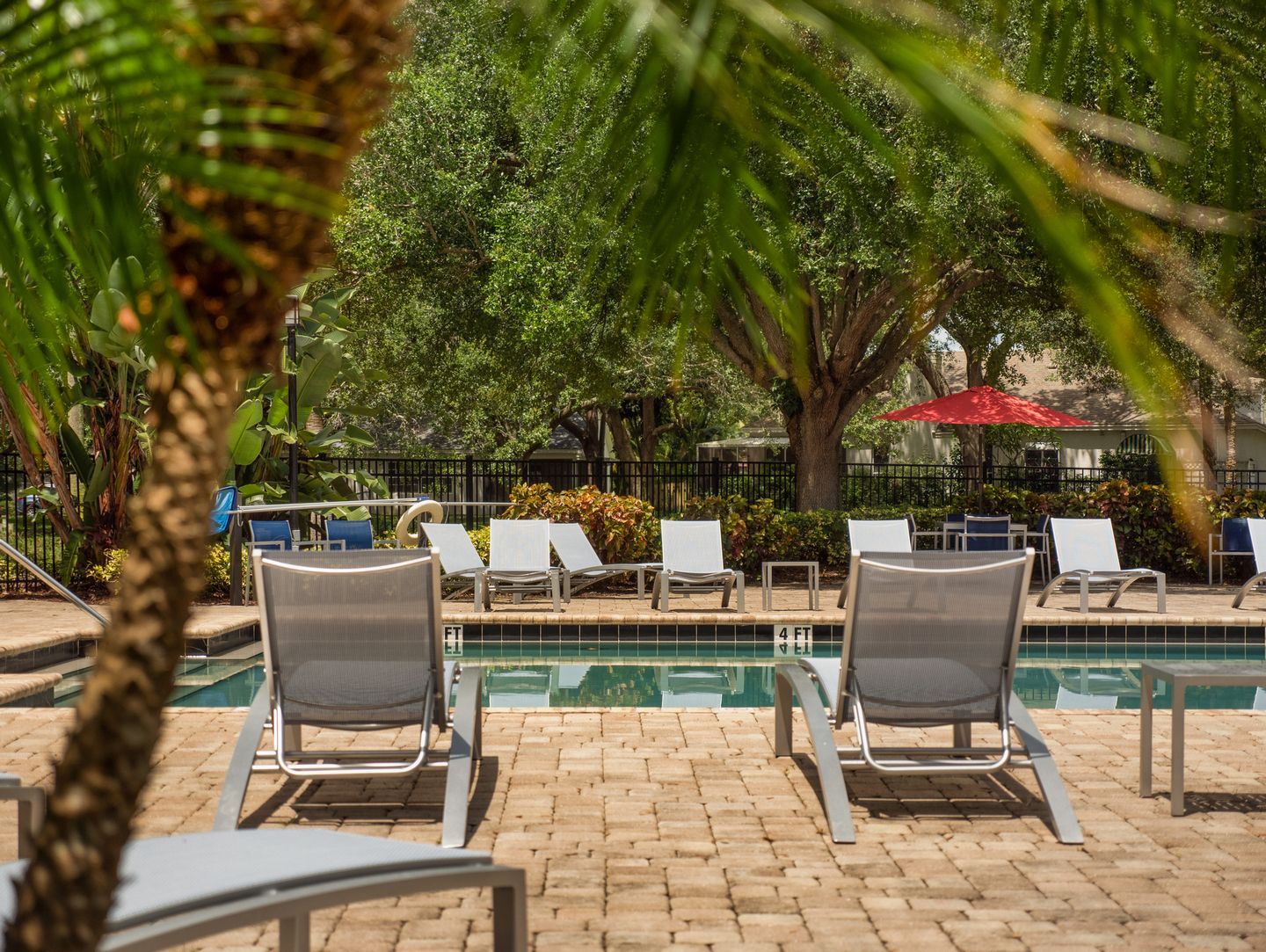 Poolside scene with lounge chairs, brick patio, and green trees. Step into comfort at our Melbourne, FL apartments for rent and book your tour today.