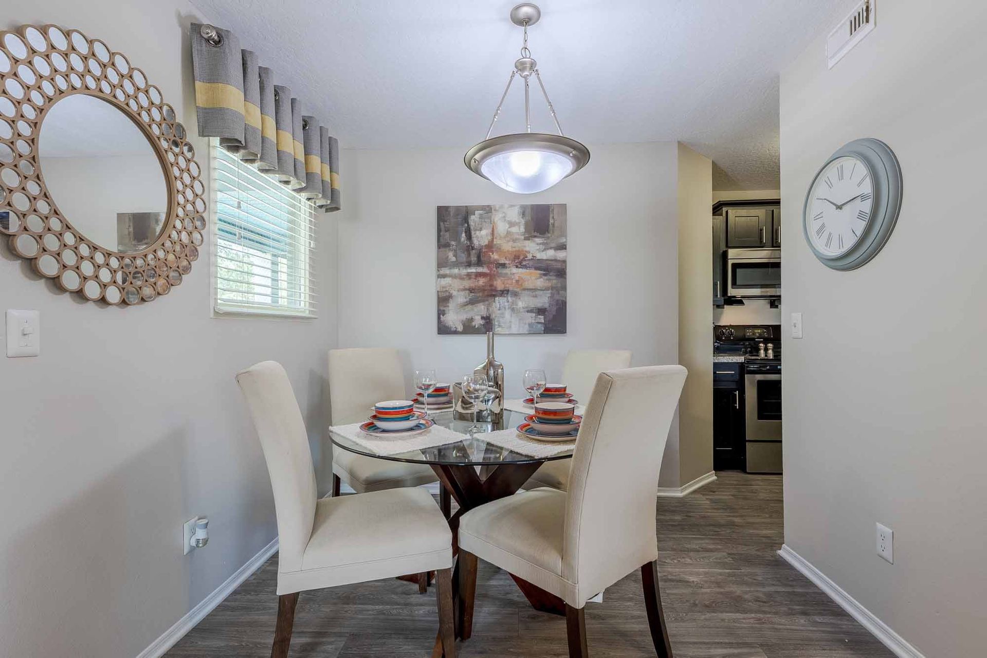 Dining room with a round table, four chairs, and a clock. Step inside our thoughtfully designed 1-bedroom apartments in Melbourne, FL and schedule your visit today.