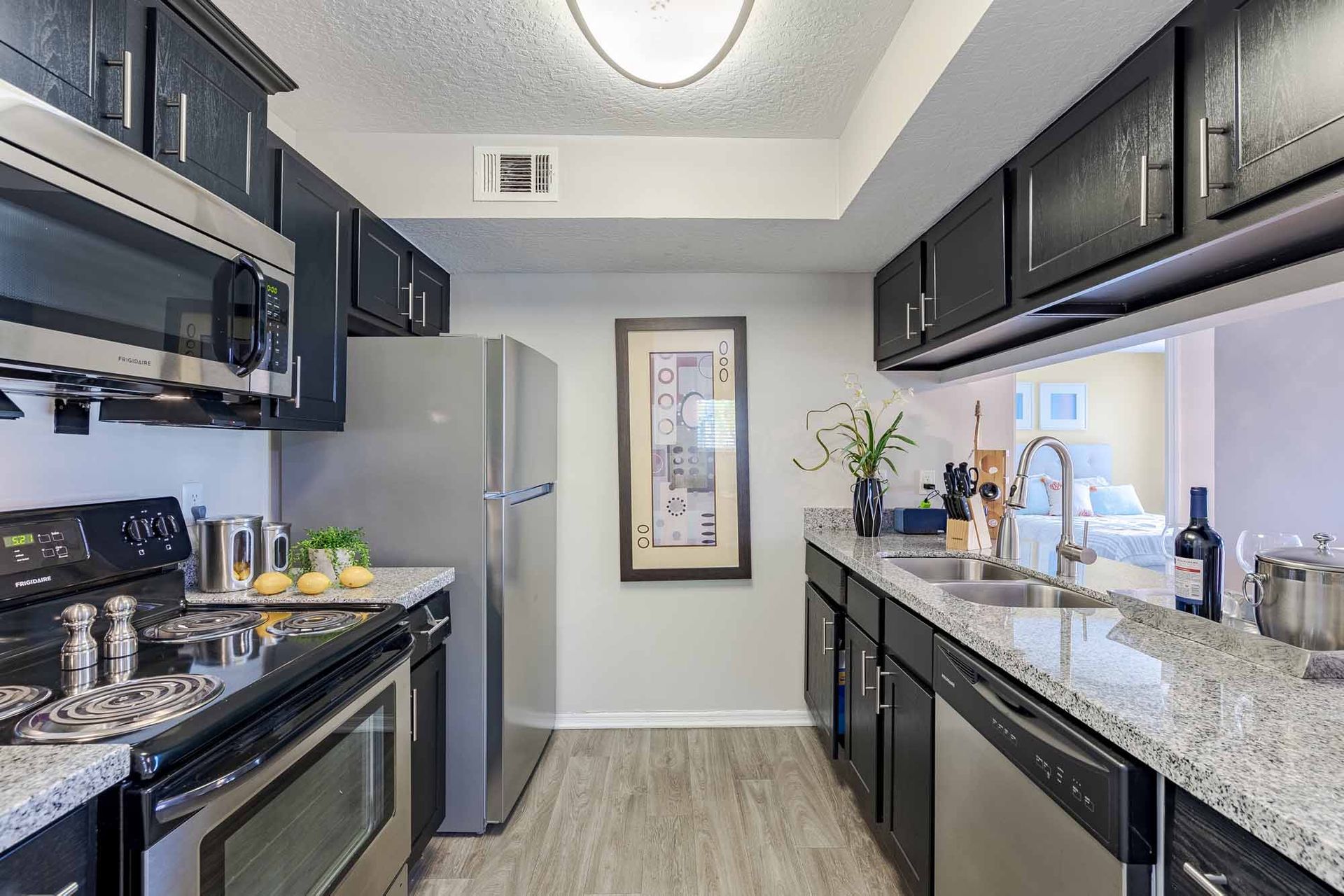 Modern kitchen with dark cabinets, stainless steel appliances, and gray countertops. Schedule a tour today and explore why these are some of the most inviting Apartments in Melbourne, FL at Savannahs at James Landing.