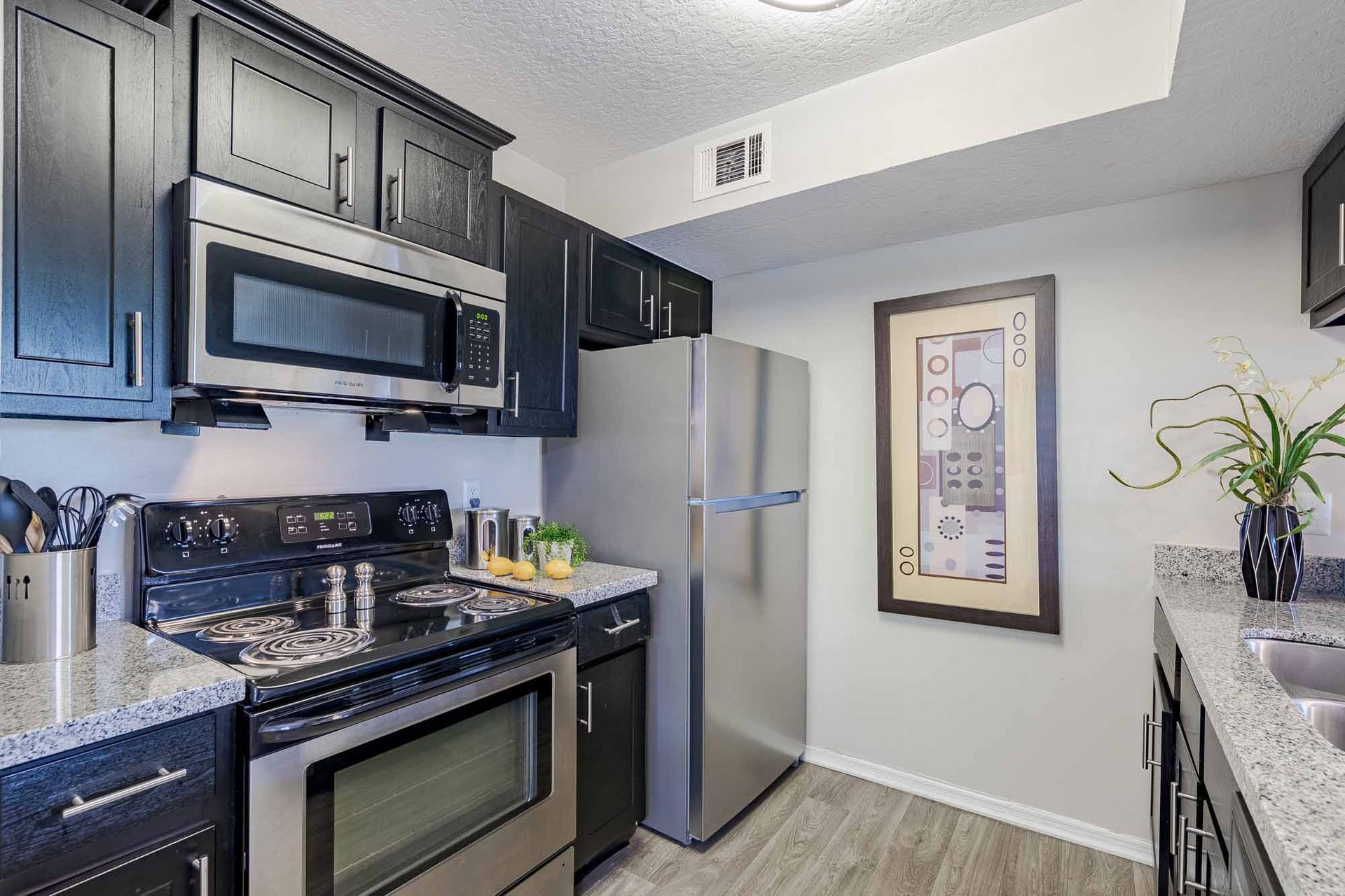 Kitchen with black cabinets, stainless steel appliances, and gray countertops. Come see these beautifully designed Melbourne, FL apartments in person and experience the lifestyle for yourself.