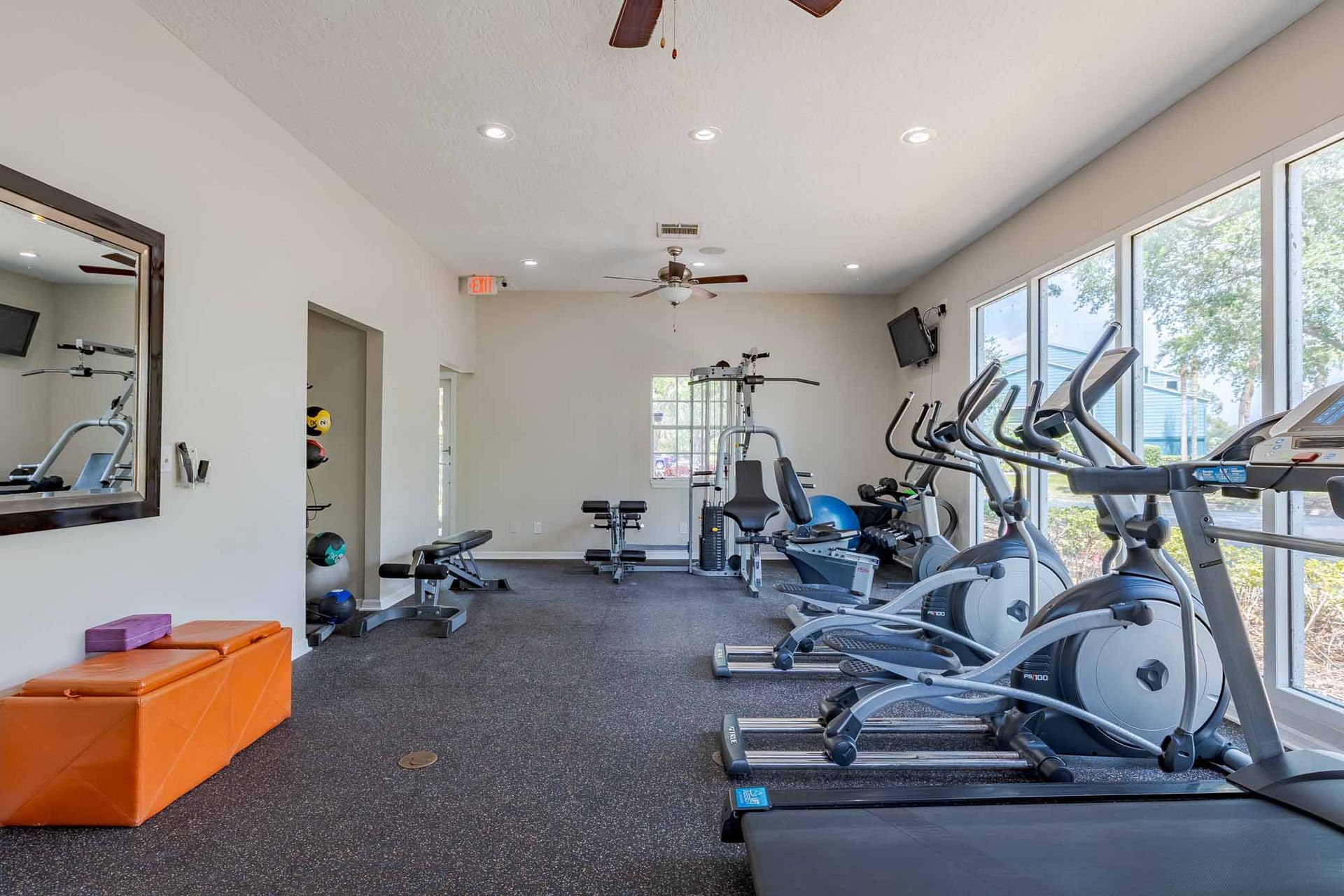 Gym with exercise equipment, including treadmills and weights, near large windows. Discover the charm of these Melbourne, FL apartments when you visit Savannahs at James Landing.