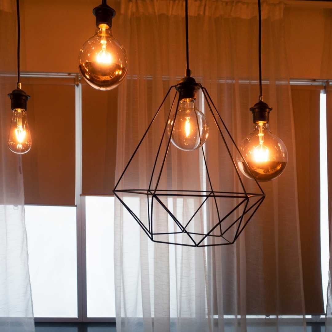 A bunch of light bulbs hanging from the ceiling in front of a window