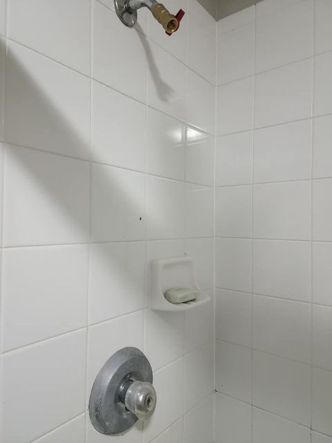 A shower with white tiles and a soap dish