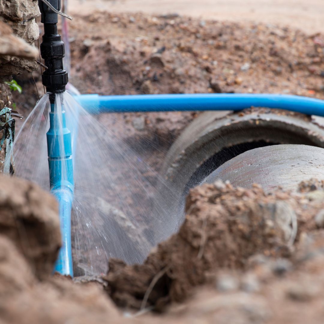 A blue pipe is leaking water in the dirt.