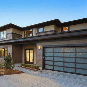 A two-story modern house with horizontal brown siding, a glass-paneled garage door, and a front entry under a porch.