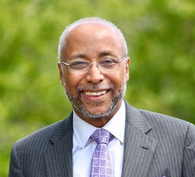 Arthur W. Harmon Jr., in a suit and tie, is smiling for the camera.