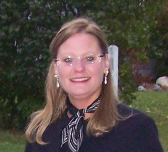 A woman wearing glasses and a scarf smiles for the camera