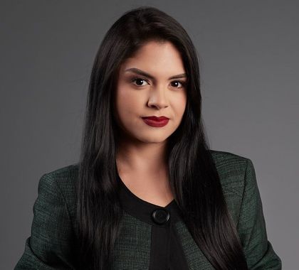 A woman with long black hair is wearing a green jacket and red lipstick.