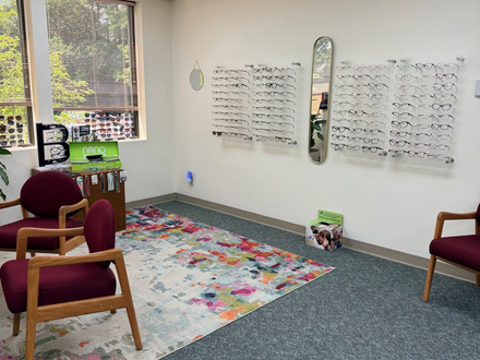 Quiet waiting room with black chairs, small table, bulletin board, and coat hooks on mint green walls.