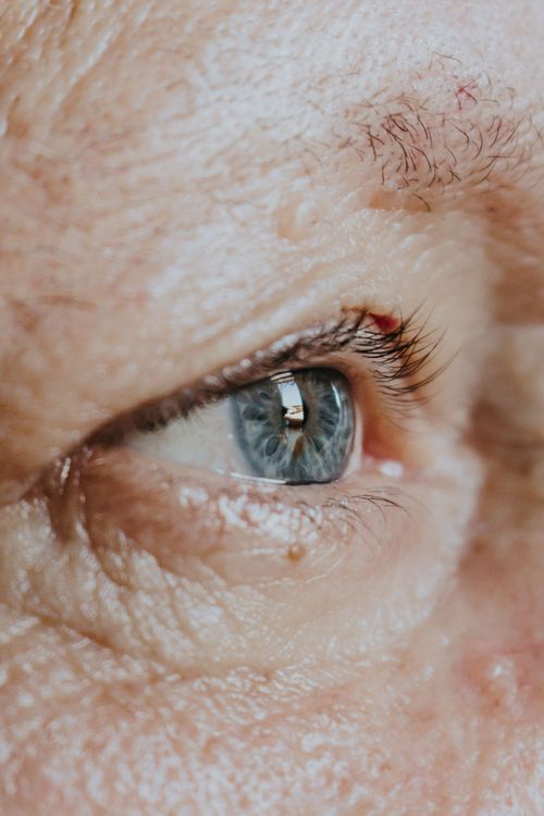Close-up of a blue eye with wrinkles and a light eyebrow.