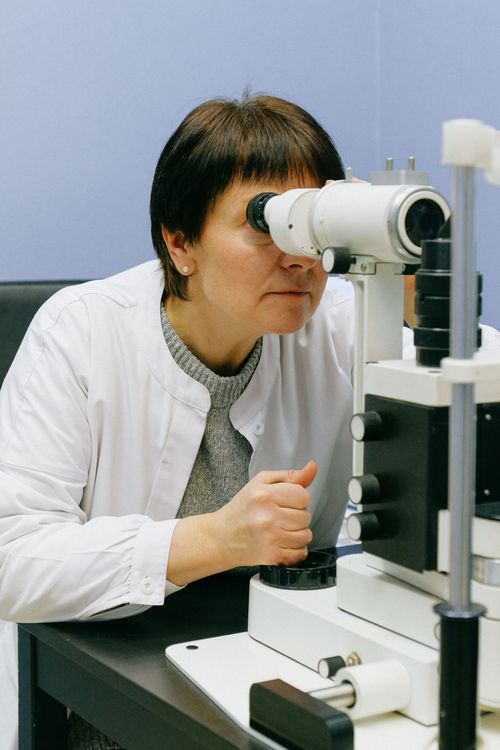 Scientist looking into a microscope in a lab, wearing a white lab coat