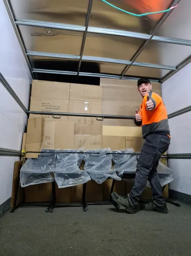 Orange forklift moving stacked blue pallets in a warehouse yard