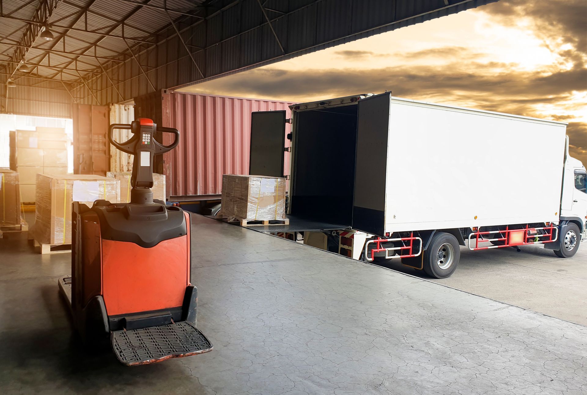 Forklift beside a white box truck inside a warehouse loading dock Forklift beside a white box truck inside a warehouse loading dock