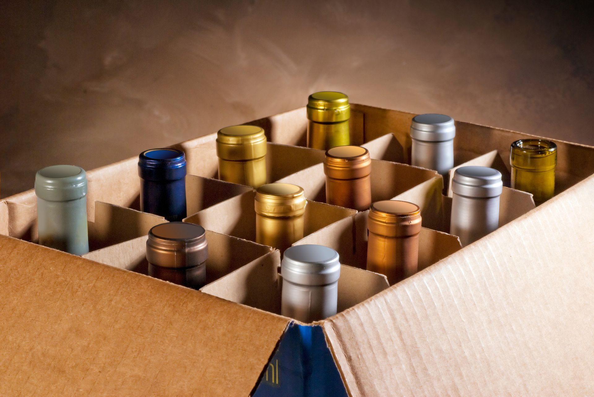 Open cardboard box filled with assorted metallic bottles and jars in gold, silver, blue, and copper. Open cardboard box filled with assorted metallic bottles and jars in gold, silver, blue, and copper.