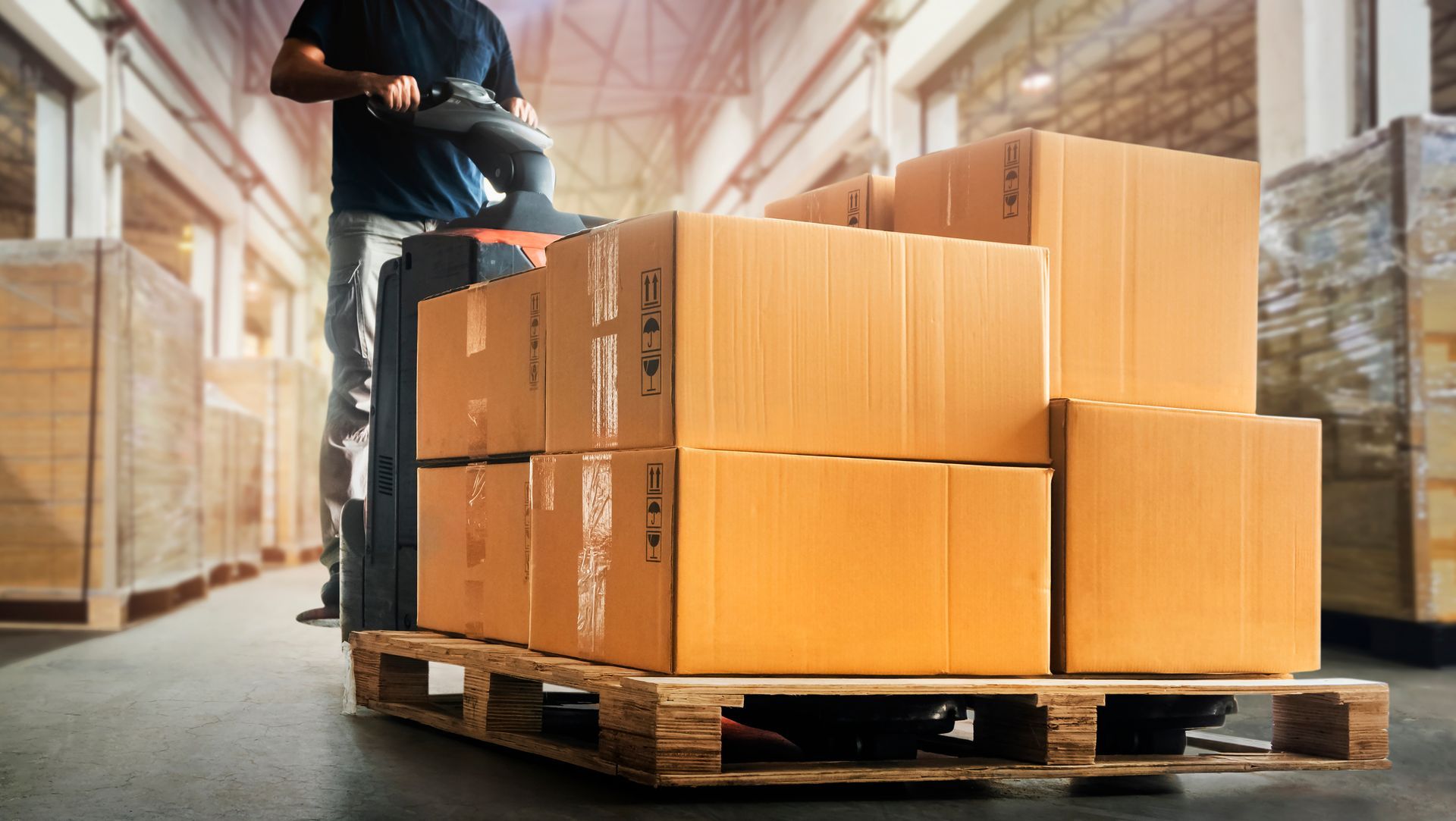 Worker stacking cardboard boxes on a pallet in a warehouse loading area Worker stacking cardboard boxes on a pallet in a warehouse loading area