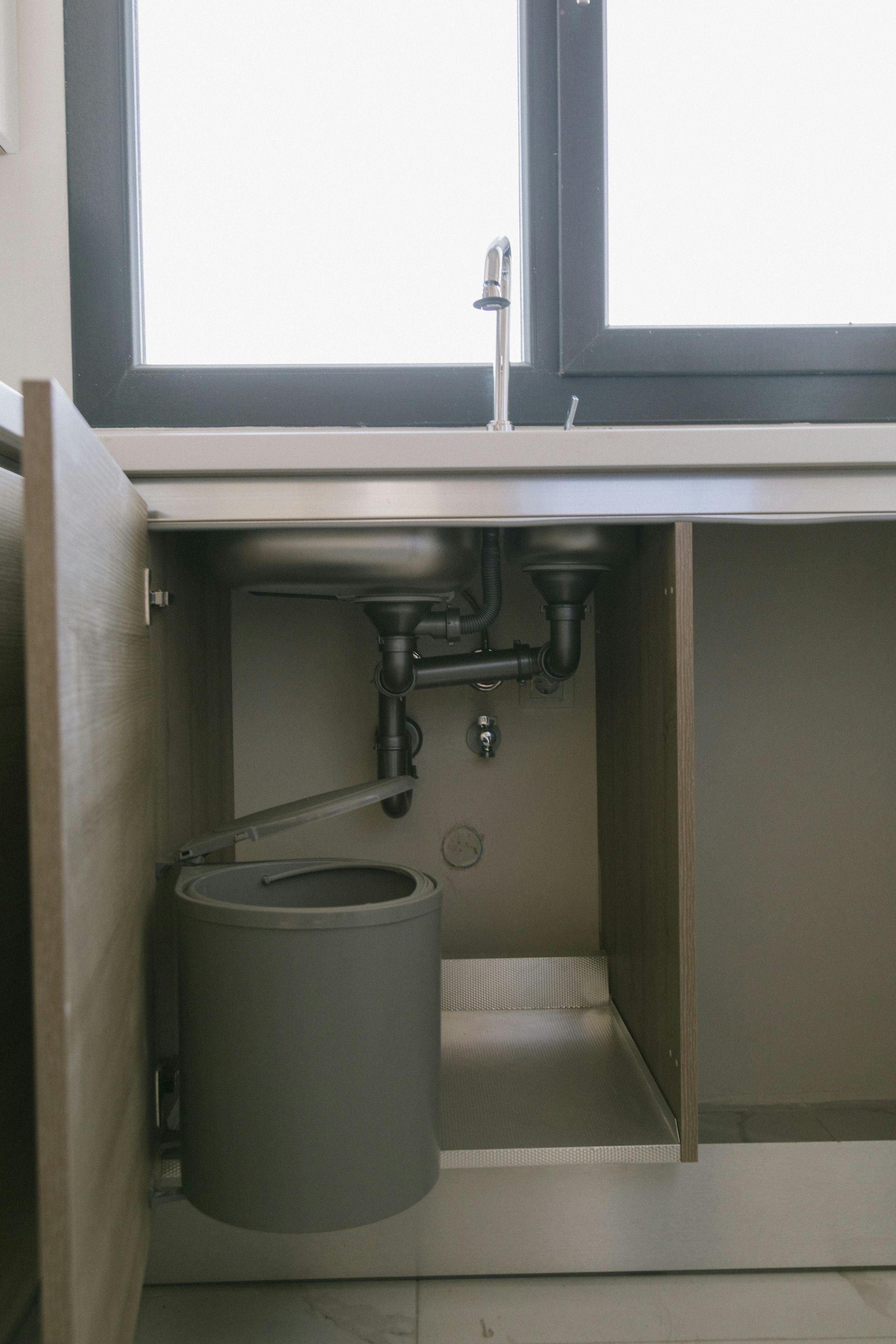 Under-sink pipes and P-trap exposed in open cabinet—clog/leak alert for Hammond, IN plumbers.
