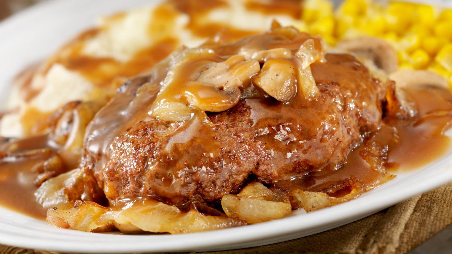A close up of a plate of food with meat and gravy on a table.