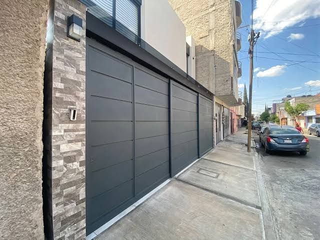 Primer plano de un pestillo de puerta de metal negro con pomo estriado en una acera de la ciudad.
