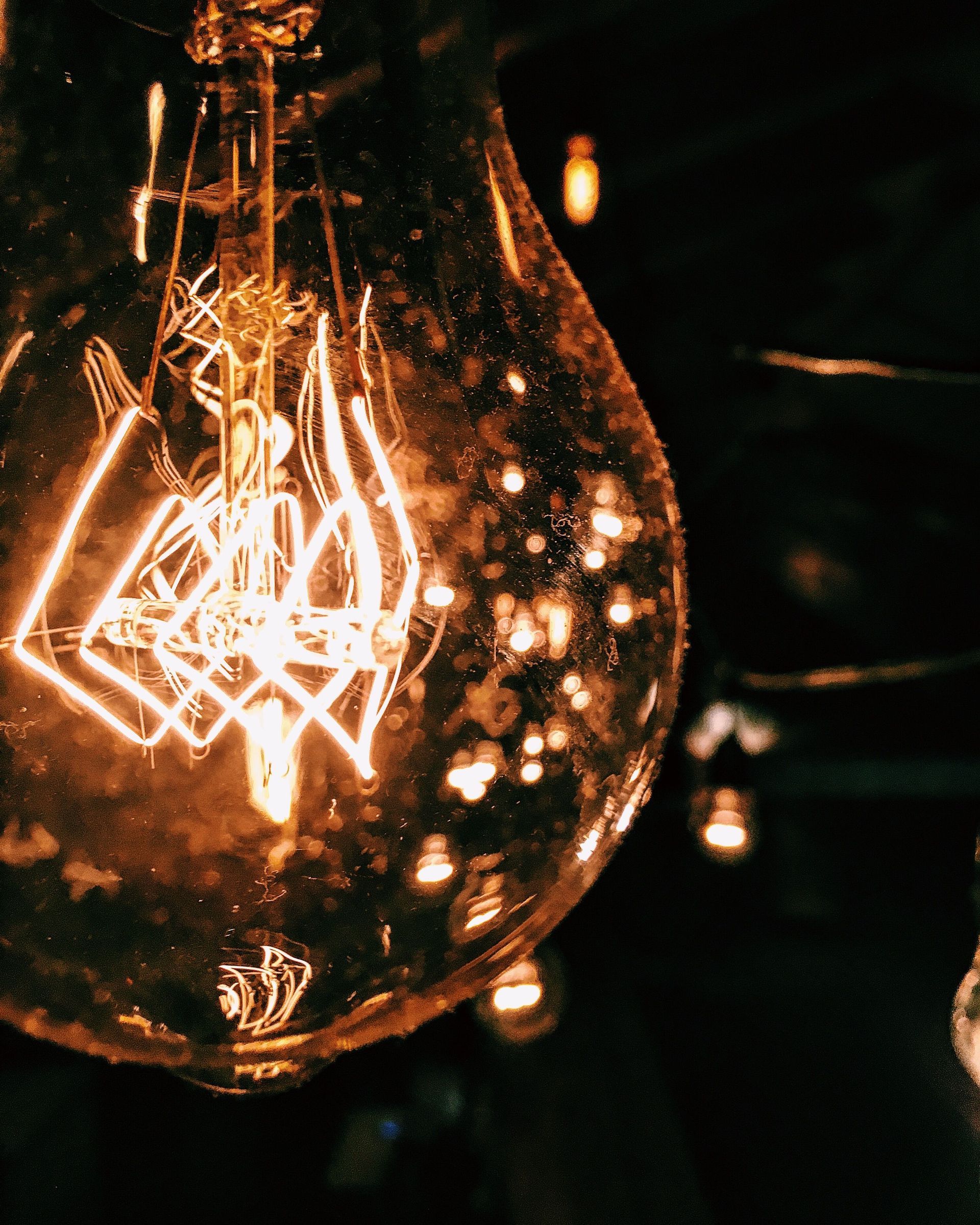 Close-up of a glowing vintage light bulb with visible filament in a dark setting