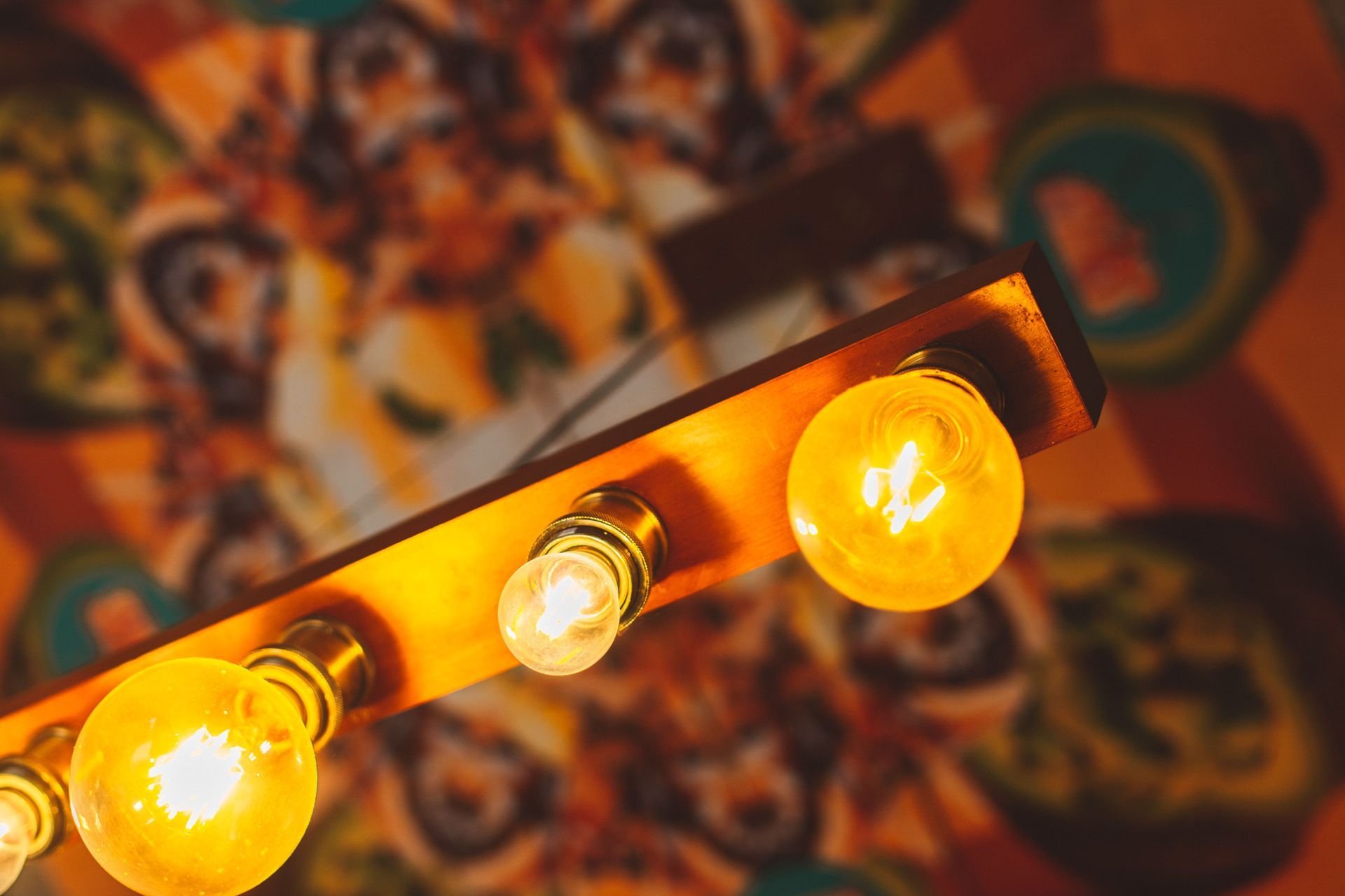 Warm yellow bulbs glowing on a tilted string light bar against a blurred colorful background
