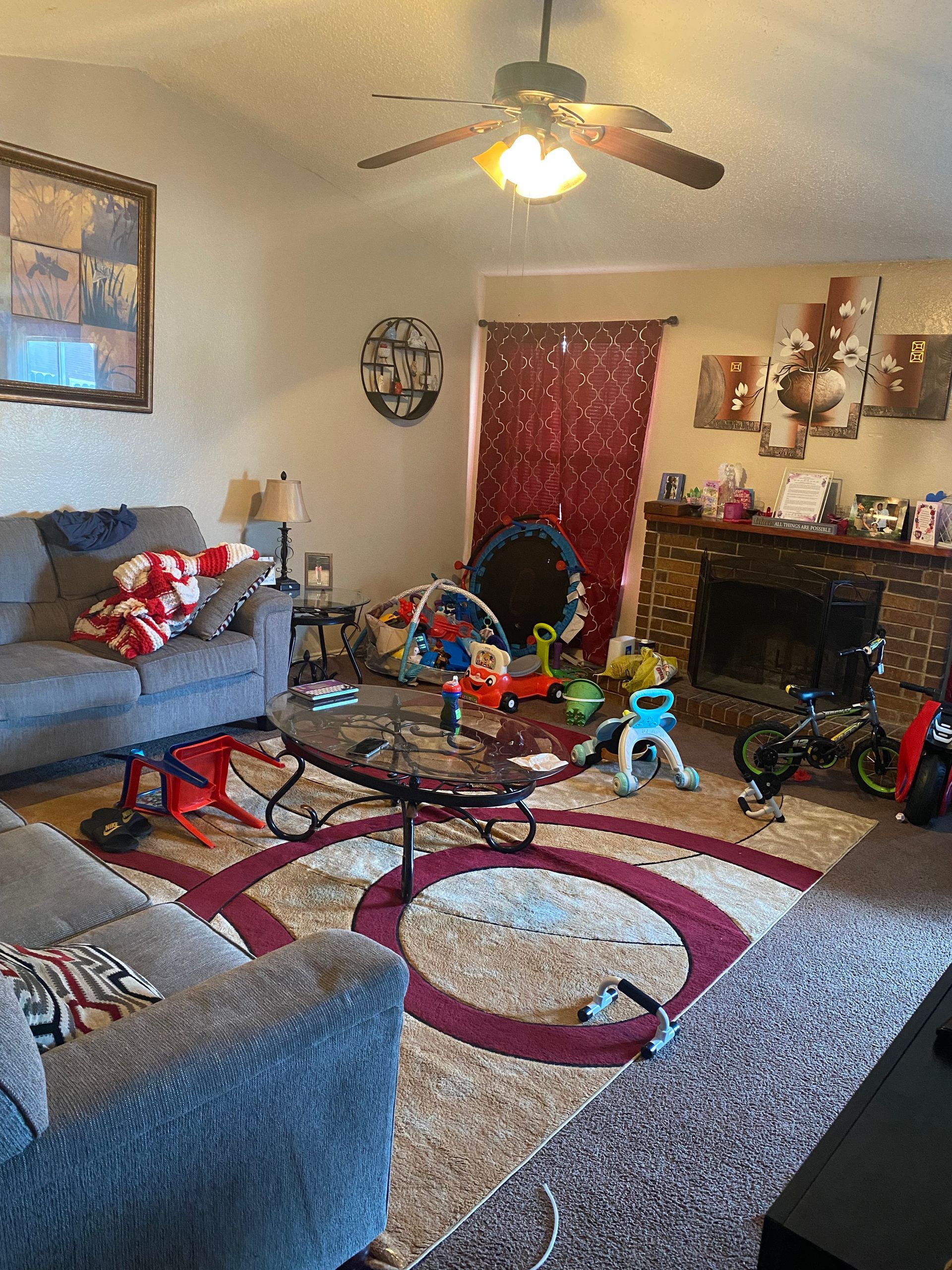 Living room with sofa, coffee table, fireplace, rug, and toys scattered about.