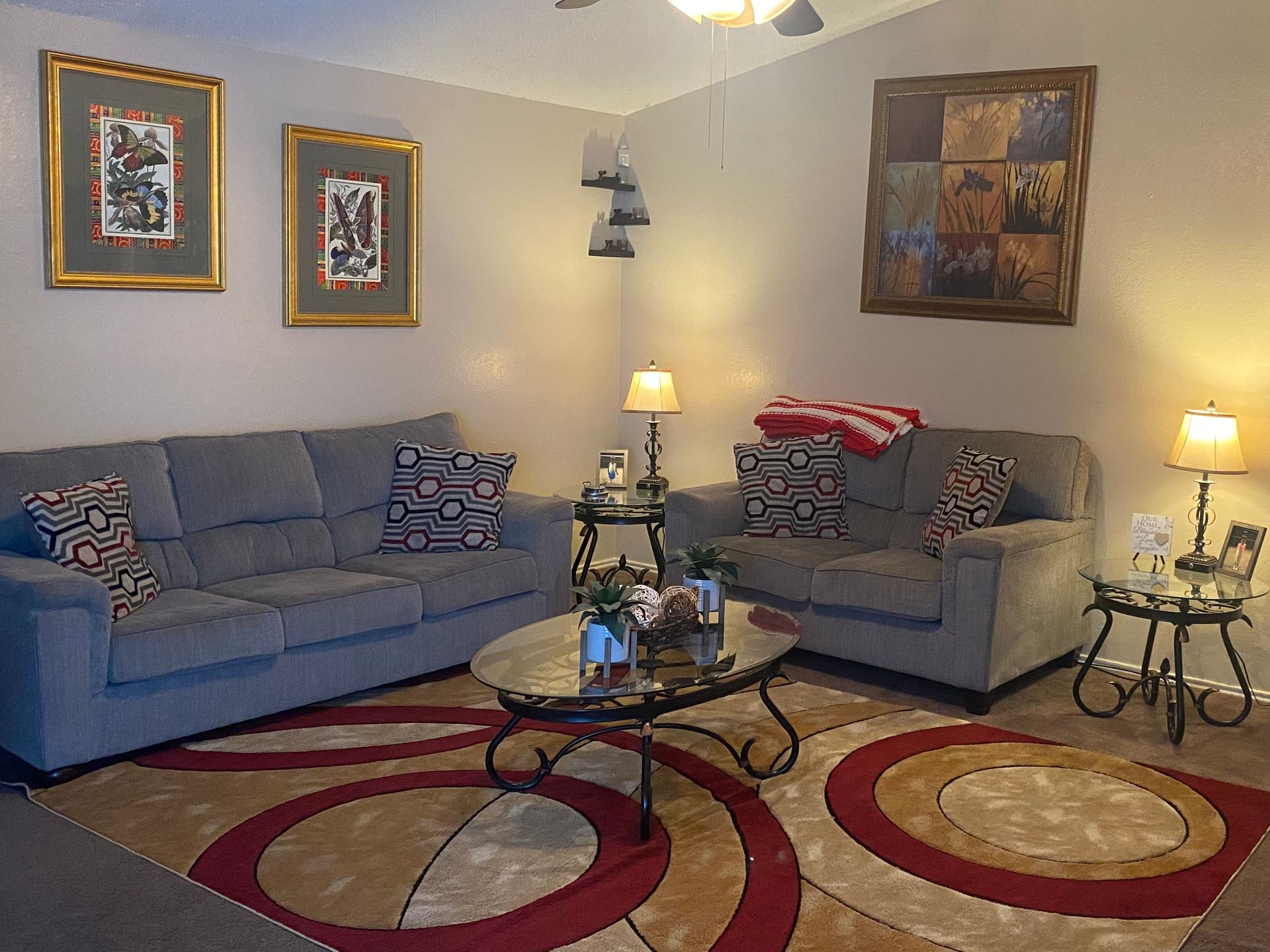 Living room with gray sofas, a patterned rug, framed art, and decorative side tables.